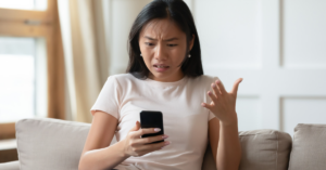how to overcome perfectionism. woman frustrated, holding phone in hand.